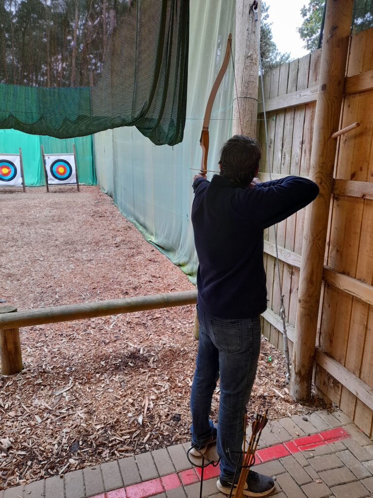 A photo of my husband having a go at archery with the target visible in the distance