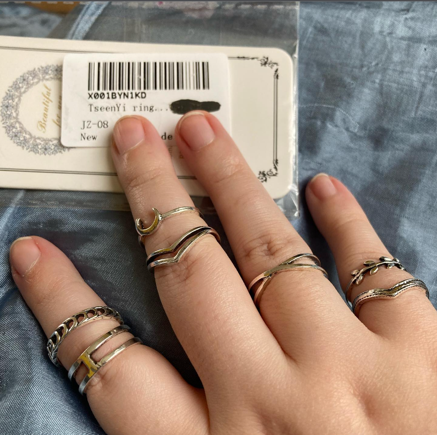 a photo of Hawke's hand wearing a few silver rings of varying patterns and showing the label and packaging that they came with, where part of it has been blacked out with marker pen.