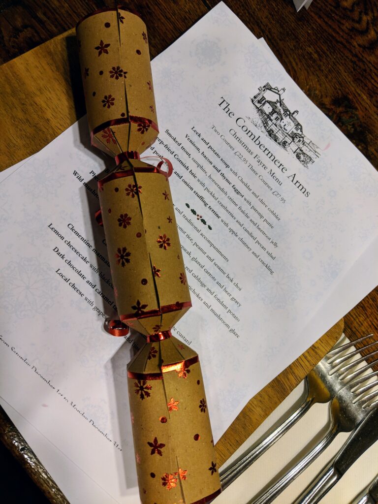 a christmas cracker sits on top of a menu for the Combermere Arms.