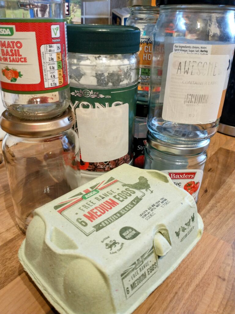 a selection of different sizes of jar stacked behind an egg box. Some of the jars have a label on reading "Awesome Wales container label."