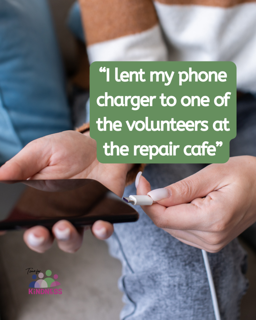 A hand about to plug a charger into a phone. Text overlaid reads “I lent my phone charger to one of the volunteers at the repair cafe.”