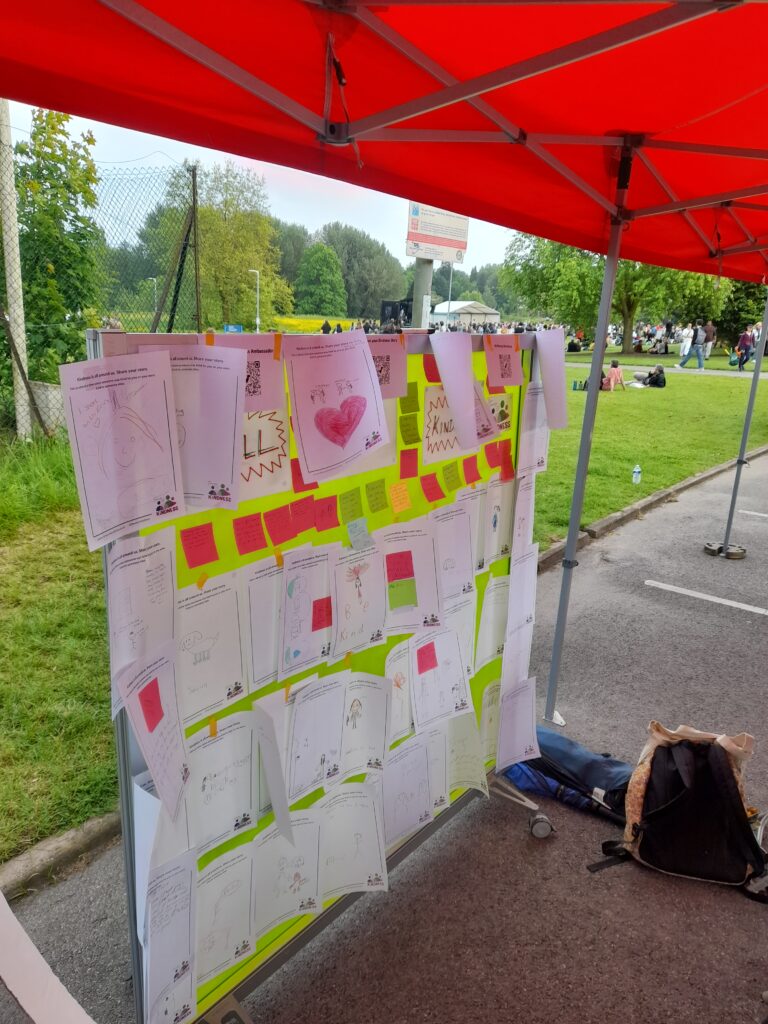 the wall of kindness at the back of the Time for Kindness stall covered in story sheets and post its all with a story of kindness on them.