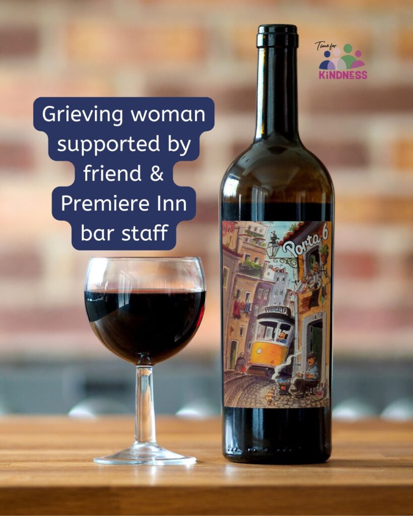 A glass and bottle of red wine on a table. Text overlaid reads “Grieving woman supported by friend & Premiere Inn bar staff.”