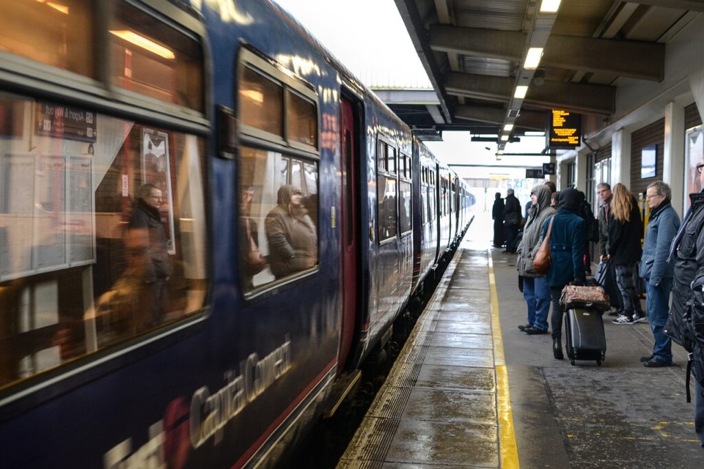 a train platform with people on it waiting as a train pulls up.