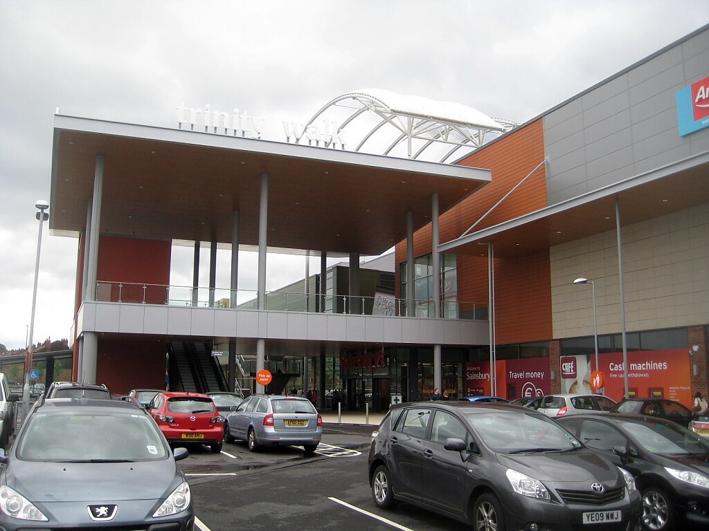 a busy car park outside a two story shopping centre.
