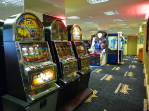 An amusement arcade with some slot machines in the foreground and other machines in the background.