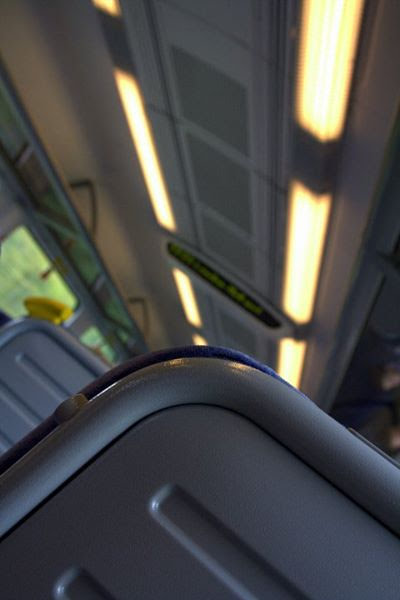 the back of a train seat in the foreground with the rest of the carriage out of focus beyond it, including the sign showing where the train is going.