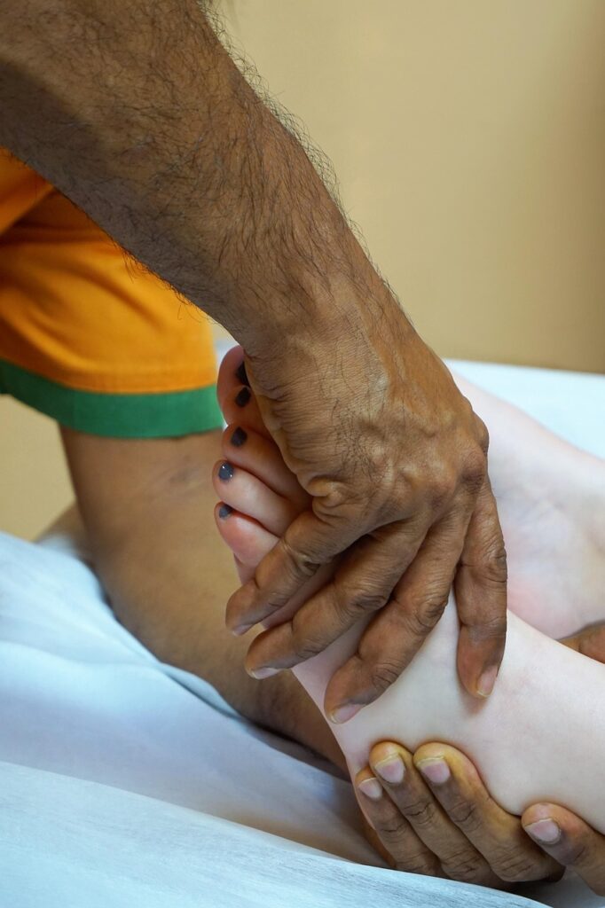 A close up of medium skin tone hands around a light skin tone foot.