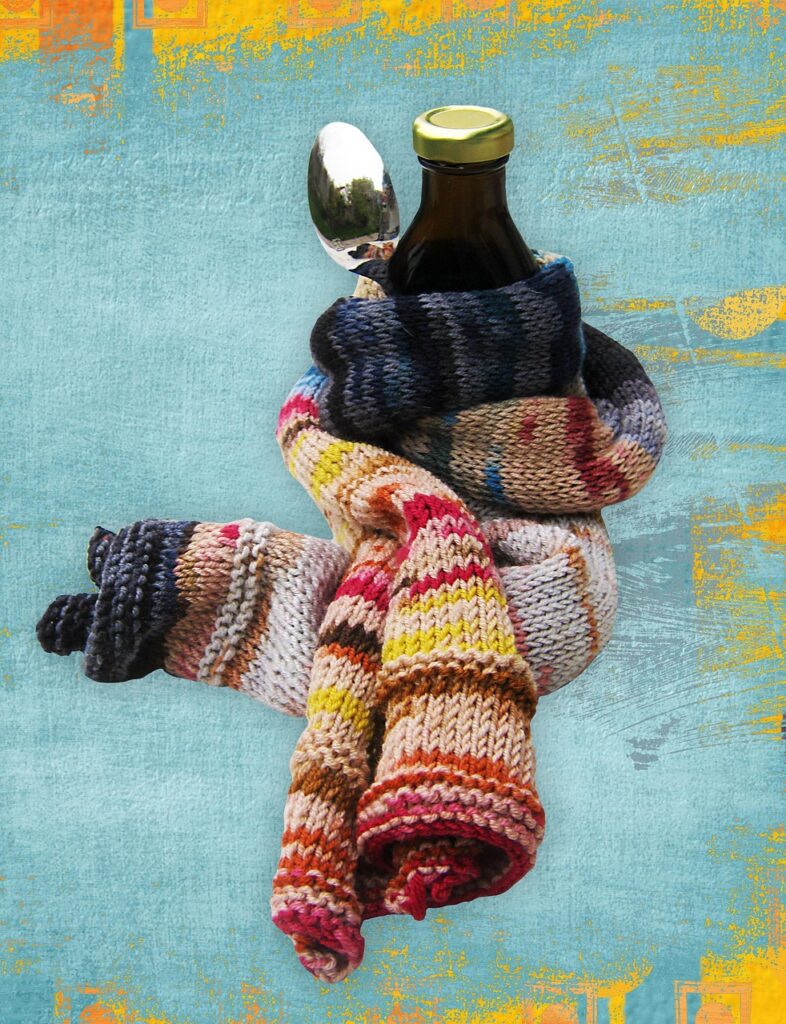 a bottle of cough syrup and a spoon wrapped in a multicoloured scarf.
