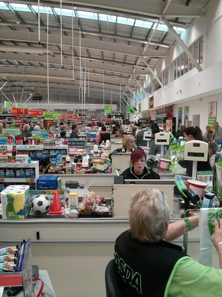 View across lots of Asda checkouts with staff sat at each and conveyor belts filled with items way into the distance. It looks like a busy shopping day.]