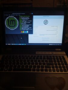 a laptop open to show the screen which has the Linux Mint info on it and the terminal open to show the Mint logo and information.