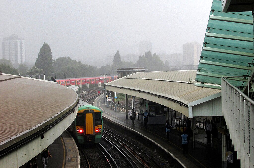 view from the over bridge at Clapham Junction train station on a rainy day as a train comes in.