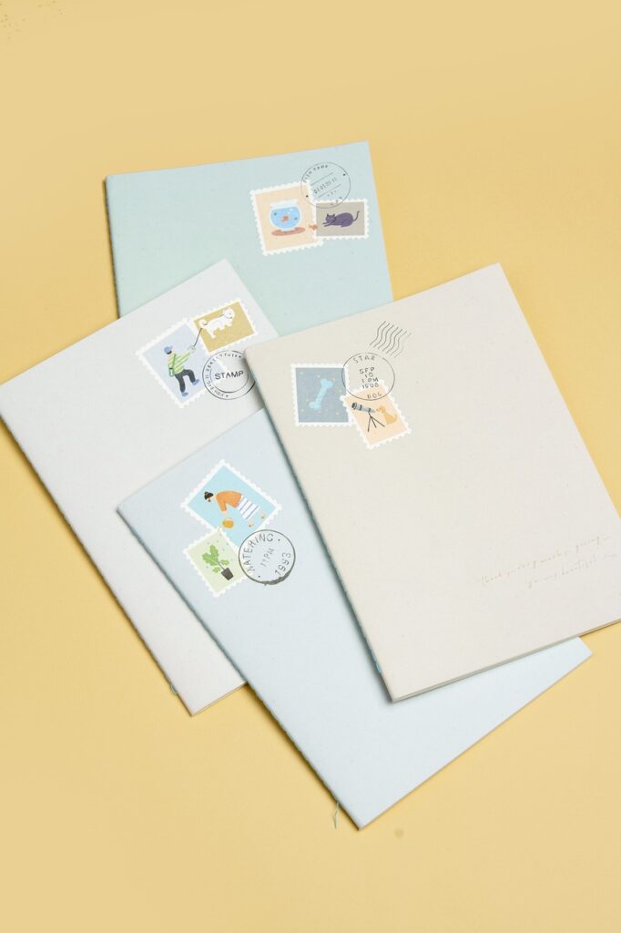 4 envelopes with stamps on laying overlapped on a pale yellow surface.