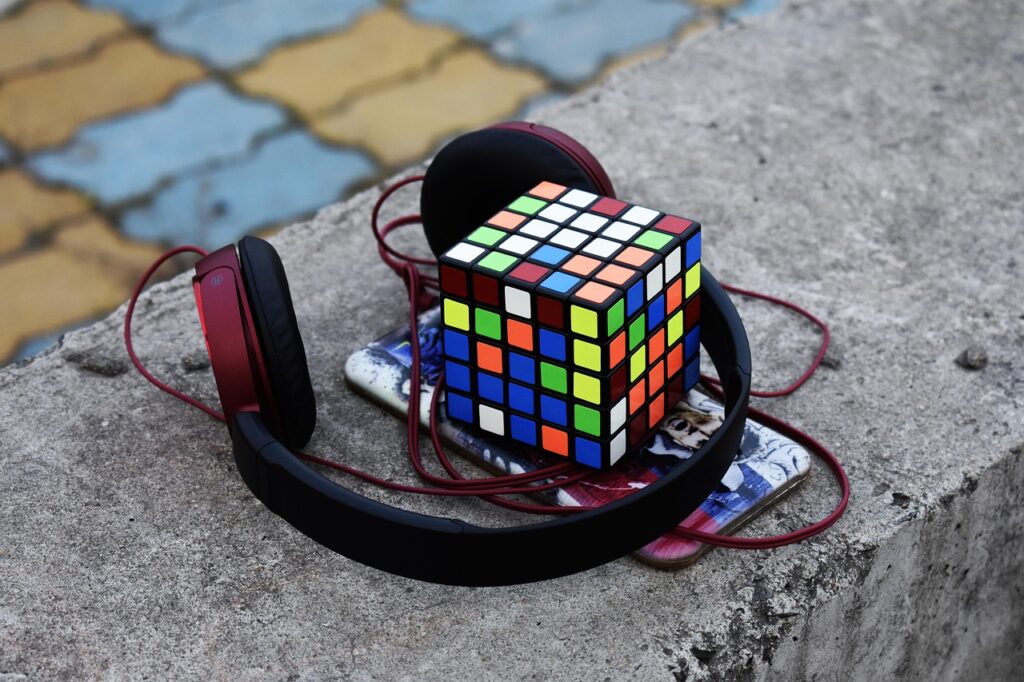 a pair of noise cancelling headphones, a Rubik’s cube and a phone sitting together on a wall.