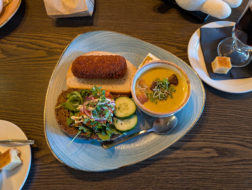 a plate with a bowl of curry soup with croquettes, meat croquette sandwich and beef spread sandwich on it.