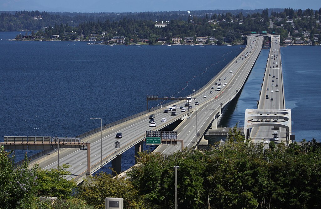 two large interstate roads over a large body of water going between States in the USA. The weather is beautiful and sunny, the water is a gorgeous blue.