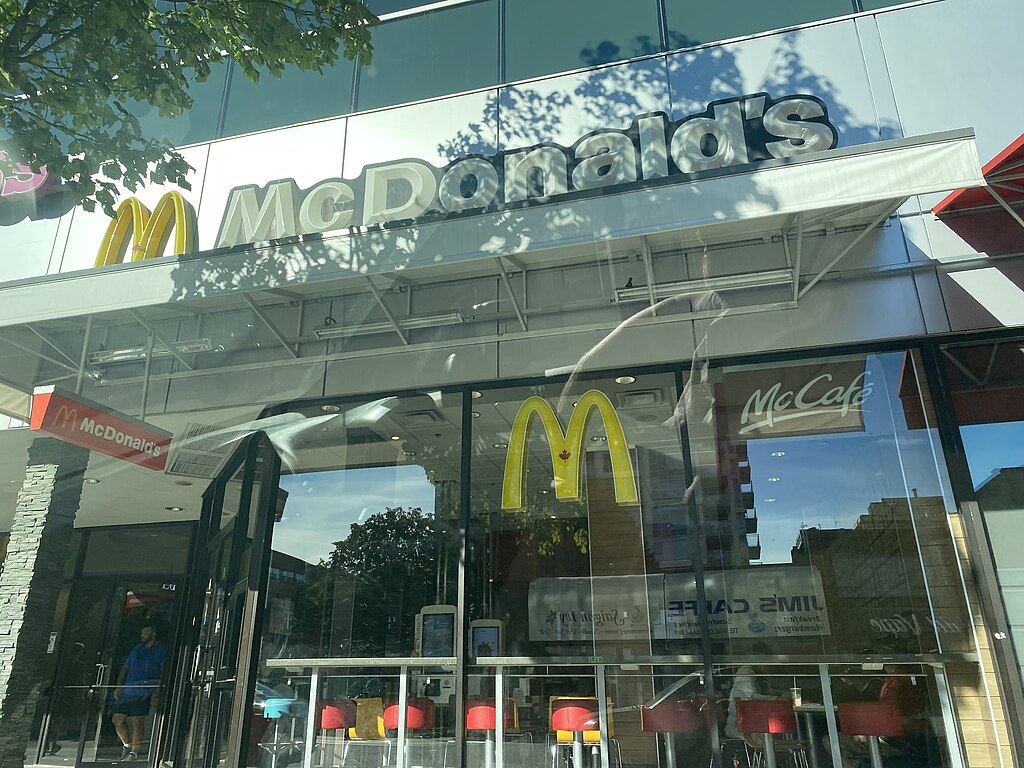 A large glass fronted McDonald’s store viewed from the outside.