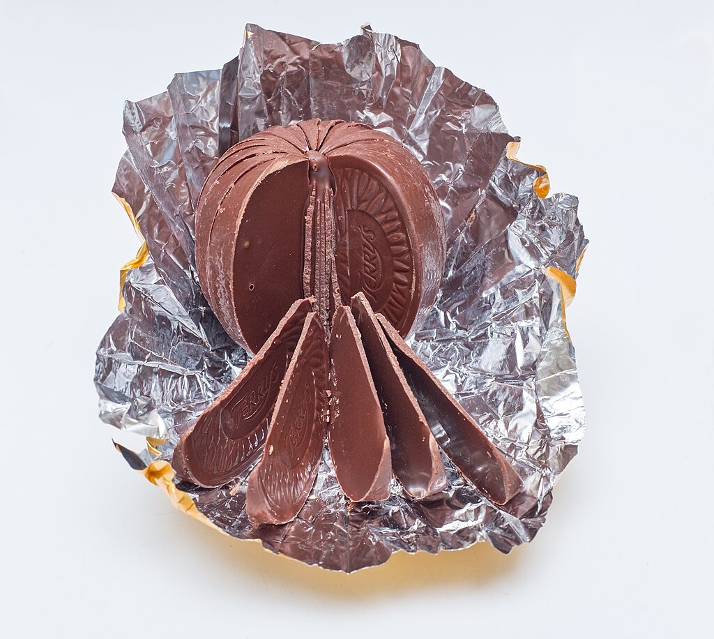 a Terry’s chocolate orange unwrapped with five slices laying outwards from it while the rest remains all together.
