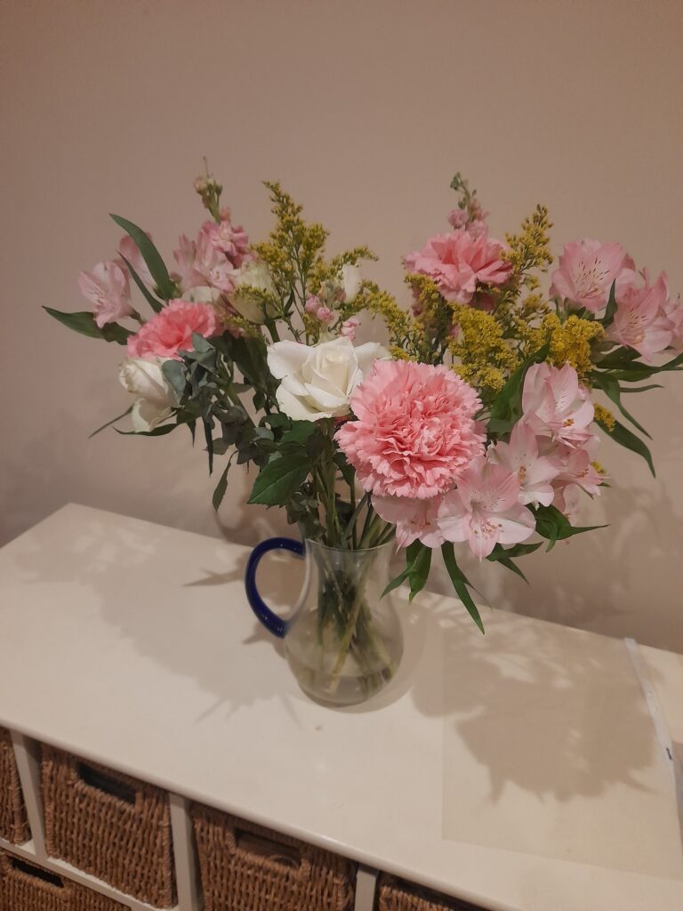 a glass jug with beautiful pink and white flowers in it.