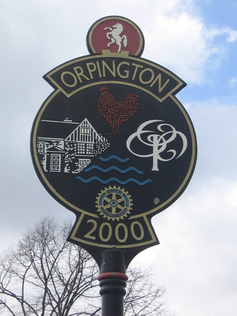 a round black sign with Orpington along the top, with a dancing horse in a red circle above it, and a rooster, pub. stylised tree, and river in the main circle of the sign, and the number 2000 below it.