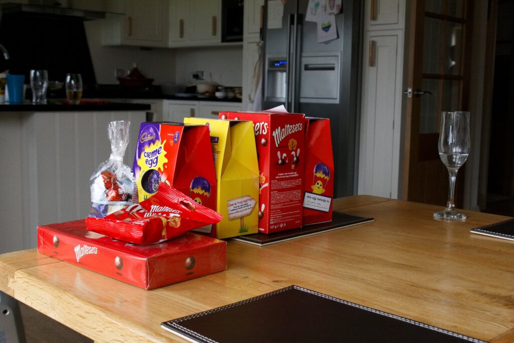A selection of four Easter eggs on a table along with a box of Malteasers and two other bags of chocolate.