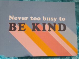A postcard which reads "Never too busy to be kind"